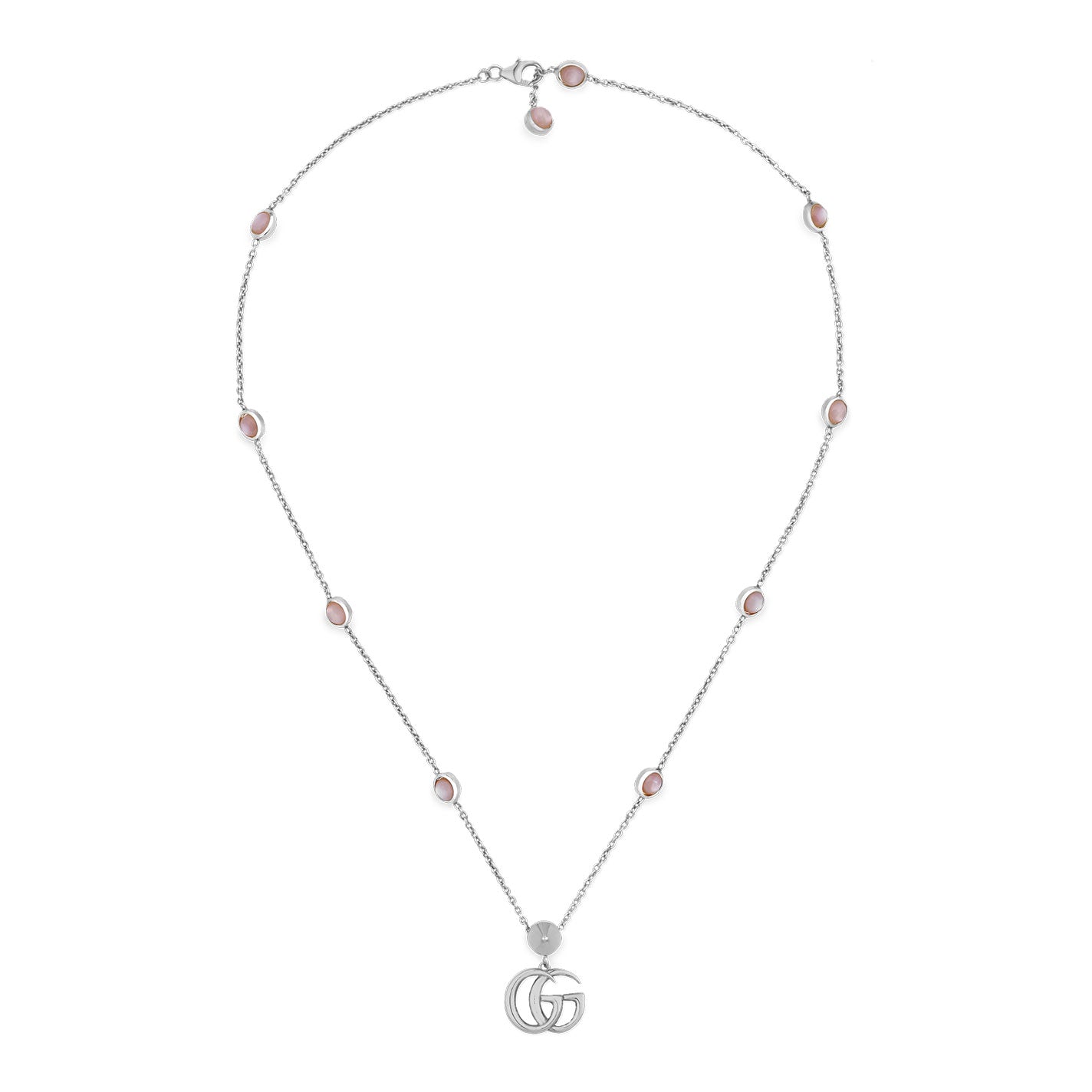 The GUCCI Fine Jewellery piece, the Gucci Double G Pink Mother of Pearl Sterling Silver Station Necklace Pendant, showcases a sterling silver chain embellished with small, round pink mother of pearl stones evenly arranged along its length. Centrally placed is an iconic Double G pendant. The necklace is gracefully presented in an open loop against a white background.