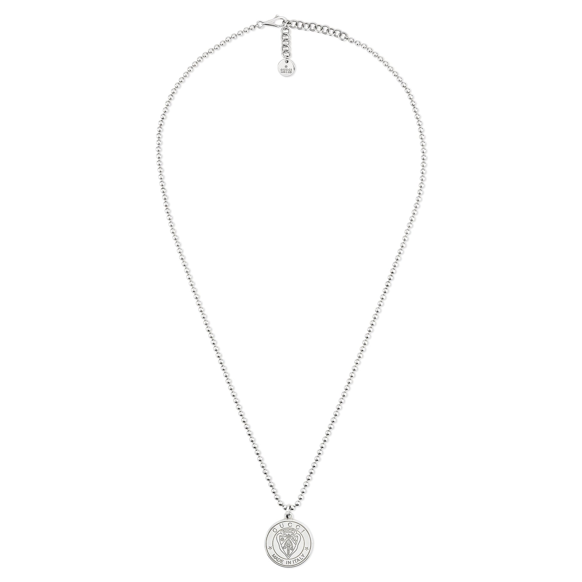 The Gucci Crest Sterling Silver Necklace Pendant by GUCCI Fine Jewellery features a detailed round pendant inspired by the Gucci crest, an adjustable clasp, and a small tag at the end.