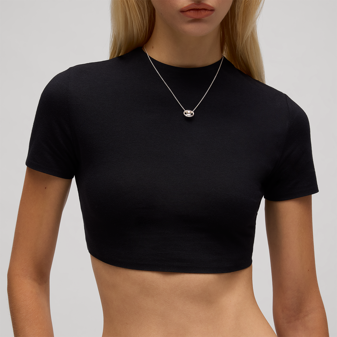 A person wears a Gucci Marina Sterling Silver Chain Necklace Pendant featuring a small, circular sterling silver anchor-link pendant.