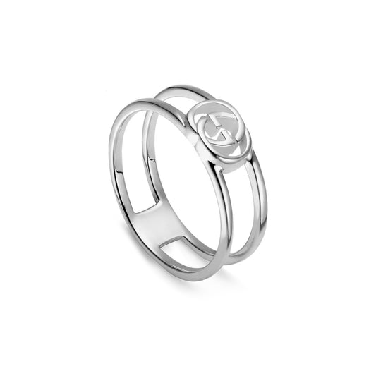 The Gucci Interlocking Sterling Silver Thin Open Band Ring from GUCCI Fine Jewellery showcases a sleek, modern design with two parallel bands joined by a central circular emblem. This emblem displays a stylized Interlocking G, honoring Guccio Gucci, and the ring features a polished finish.