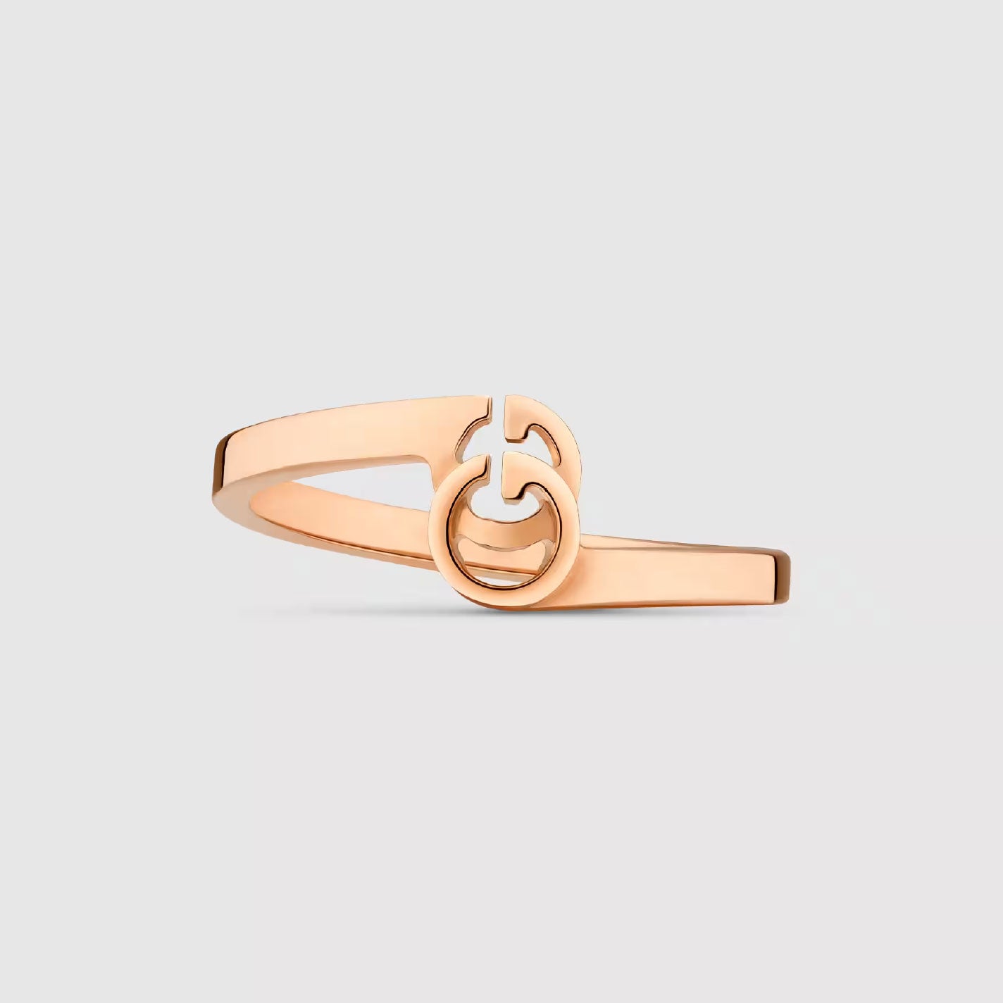 A sleek Gucci Running G 18K Rose Gold Ring from GUCCI Fine Jewellery, showcasing a modern design with an interlocking double G motif at the center and set against a plain light gray background.