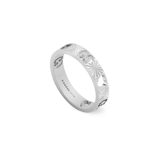 The Gucci Icon Heart 18K White Gold Ring from GUCCI Fine Jewellery features a cut-out design with alternating carved motifs and circular holes, incorporating the GG motif on the inside. It boasts a reflective, polished finish and is crafted from 18k white gold, adhering to Responsible Jewellery Council standards.