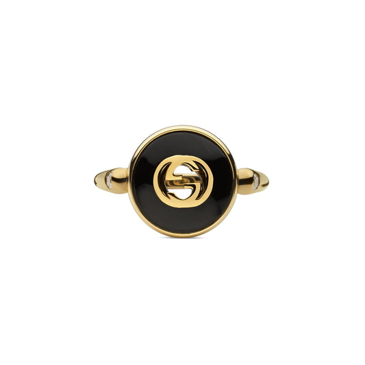 The Gucci Interlocking 18K Yellow Gold and Black Onyx Ring from GUCCI Fine Jewellery showcases a black onyx circular center adorned with a prominent interlocking double "G" logo. The sleek and polished band enhances its elegant design.