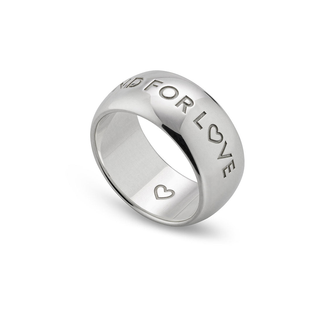 The GUCCI Fine Jewellery Blind For Love 9mm Sterling Silver Ring features "BLIND FOR LOVE" and a heart symbol engraved on the band, with a small heart inside the ring, shown on a white background.