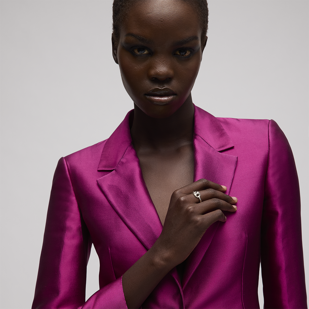 A person wearing a fuchsia blazer with a Gucci Marina Sterling Silver Chain Ring on their finger.