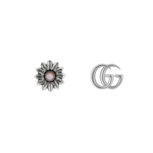 A pair of metallic objects on a white background: on the left is a silver flower with a pink center, while on the right are elegant sterling silver interlocking 'G' letters, resembling the Gucci Double G Flower Sterling Silver Stud Earrings by GUCCI Fine Jewellery.