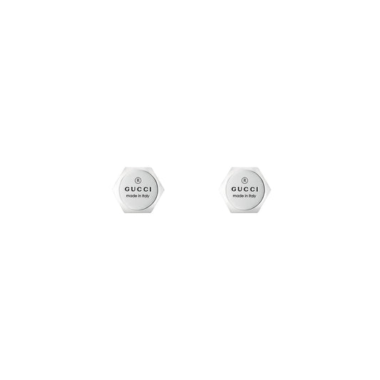 The Gucci Trademark Sterling Silver Stud Earrings by GUCCI Fine Jewellery feature two hexagonal pieces in sterling silver, showcasing the signature Gucci logo and "Made in Italy" text in black. Set against a plain white background, their minimalist design exudes timeless elegance.