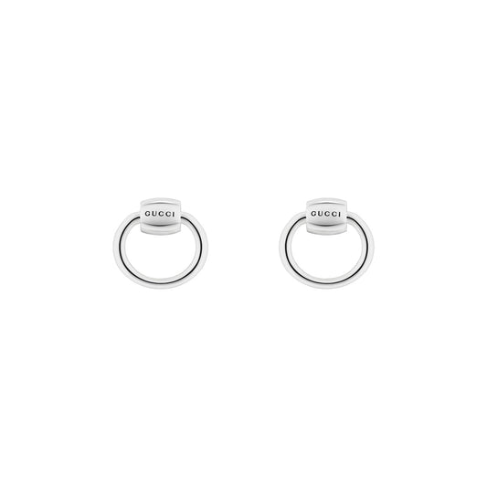 Introducing the Gucci Horsebit Sterling Silver Small Hoop Earrings by GUCCI Fine Jewellery, these elegant earrings showcase the brand's name tastefully engraved on top. The minimalist design features a small bar connecting to a larger hoop, subtly embodying an equestrian-inspired motif. Set against a simple white background, these earrings exude timeless sophistication.