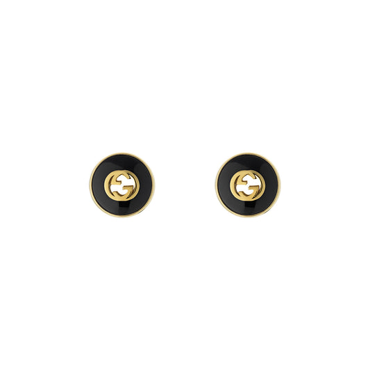 A close-up of the Gucci Interlocking G 18K Yellow Gold and Black Onyx Stud Earrings from GUCCI Fine Jewellery, featuring a striking interlocking "G" logo design in the center. The earrings boast a glossy finish that enhances their sleek and stylish look.