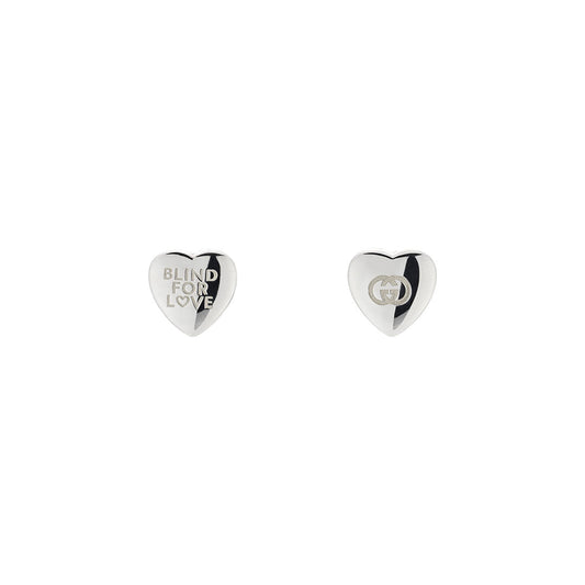 The Gucci Blind for Love Sterling Silver Stud Earrings by GUCCI Fine Jewellery feature heart shapes, with one engraved "BLIND FOR LOVE" and the other adorned with a small Gucci logo.