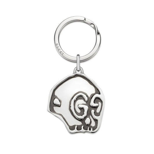 The Gucci Ghost Key Chain by GUCCI Fine Jewellery is crafted from sterling silver, featuring a stylized skull design embellished with intricate swirl patterns. The key ring is seamlessly attached to the top of the skull, blending elegance with edginess.