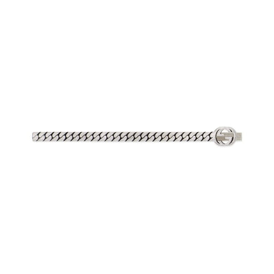 The Gucci Interlocking G Tie Bar by GUCCI Fine Jewellery is a silver accessory featuring a chain-link design and a circular emblem on the right side. This emblem showcases the interlocking G symbol, elegantly merging traditional and modern aesthetics to enhance the sophistication of this sleek piece.