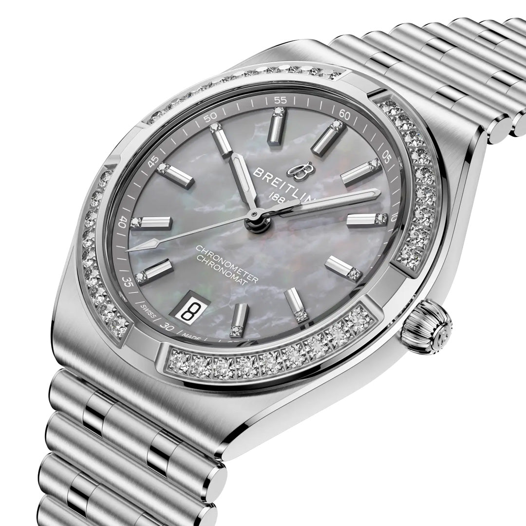 The BREITLING Chronomat Automatic 36 features a silver metal band, diamond-studded bezel, mother-of-pearl dial with silver markers, date window at 6 o'clock, and a COSC-certified face displaying “Chronometer” and “Automatic.”.