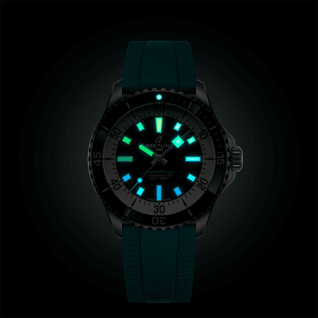 The BREITLING Superocean Automatic 42 by Breitling features luminescent Super-LumiNova dials that glow in the dark, making it ideal for scuba diving. Its dark case and textured strap enhance number visibility in a manner reminiscent of the Superocean Slow Motion style. The luminous elements create a bold contrast against the black background.