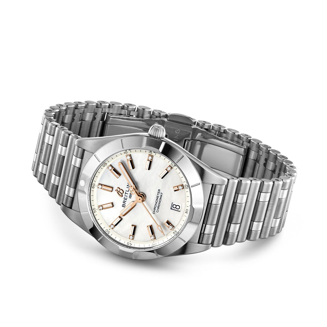 The BREITLING Chronomat 32 by Breitling features a stainless steel case, silver link bracelet, white dial with gold hour markers, and a date window at 6 o’clock, presented angled on a white background.