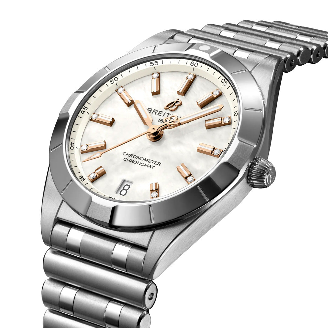 The BREITLING Chronomat 32 features a stainless steel case, diamond-set bezel, white mother-of-pearl dial with gold hour markers, date at 6 o’clock, and a metal link bracelet. The watch face is shown angled slightly to the right.
