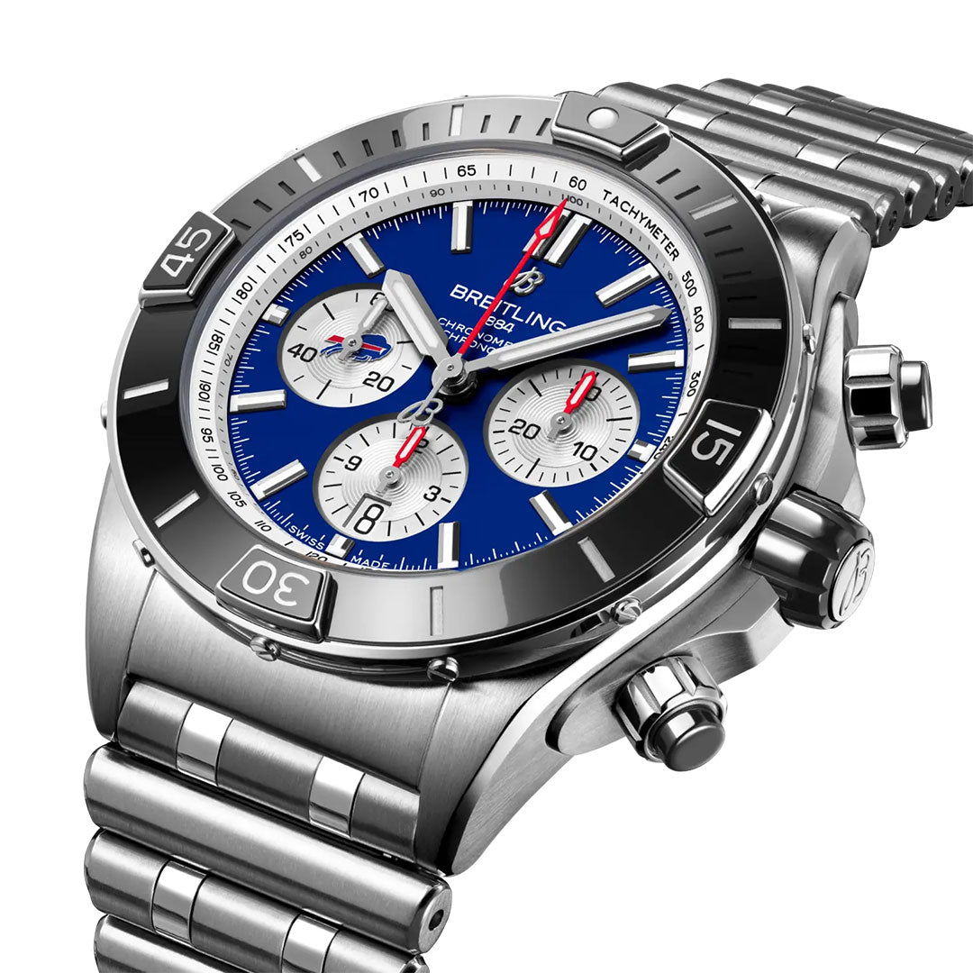The Breitling Super Chronomat B01 NFL Buffalo Bills Edition is a stainless steel luxury sports watch featuring a blue dial, three silver subdials, red and white hands, a tachymeter bezel, and a matching metal bracelet.