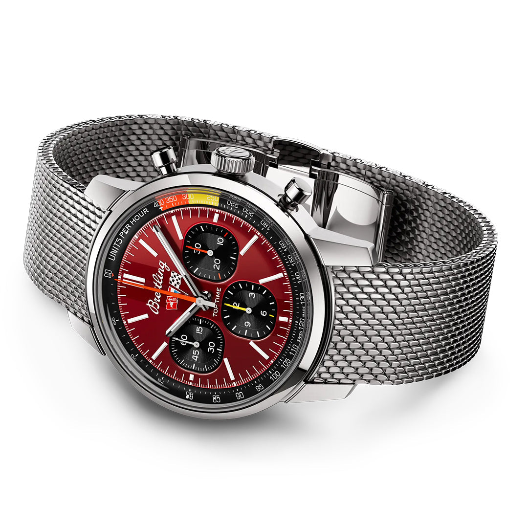 The BREITLING Top Time B01 Chevrolet Corvette luxury wristwatch boasts a round face, silver mesh band, and red dial inspired by the Chevy Corvette. It features three black subdials, silver markings, and two side buttons for easy adjustments.