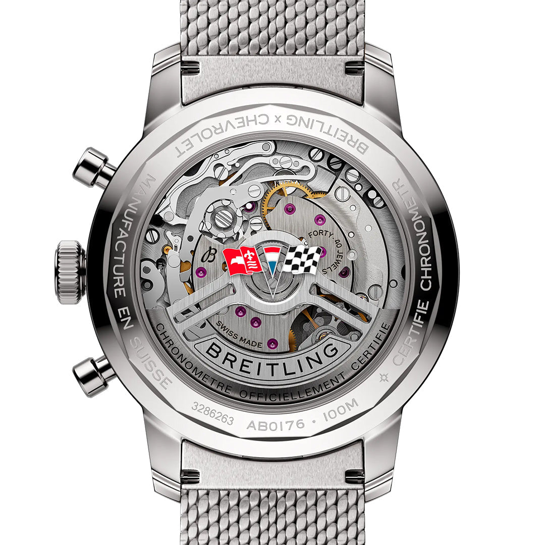 The transparent case back of the BREITLING Top Time B01 Chevrolet Corvette watch reveals its intricate mechanics, featuring engraved text like "Breitling" and "Top Time Chevrolet Corvette," along with a finely engraved red racing flag motif and Swiss details.