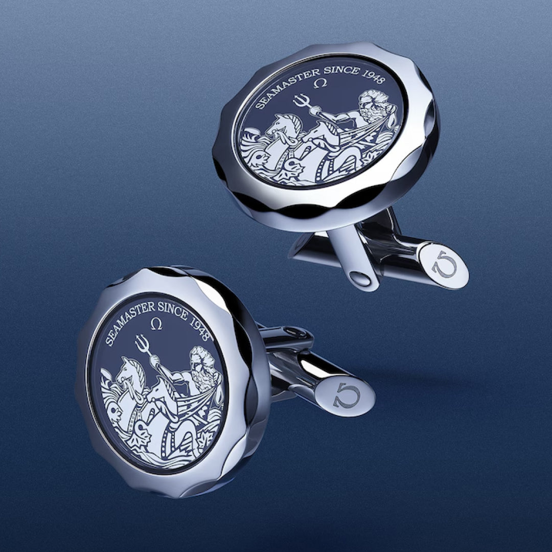 OMEGA Aqua Cufflinks, crafted from polished stainless steel with engraved designs and "SEAMASTER SINCE 1948" text, are featured on a blue gradient background.