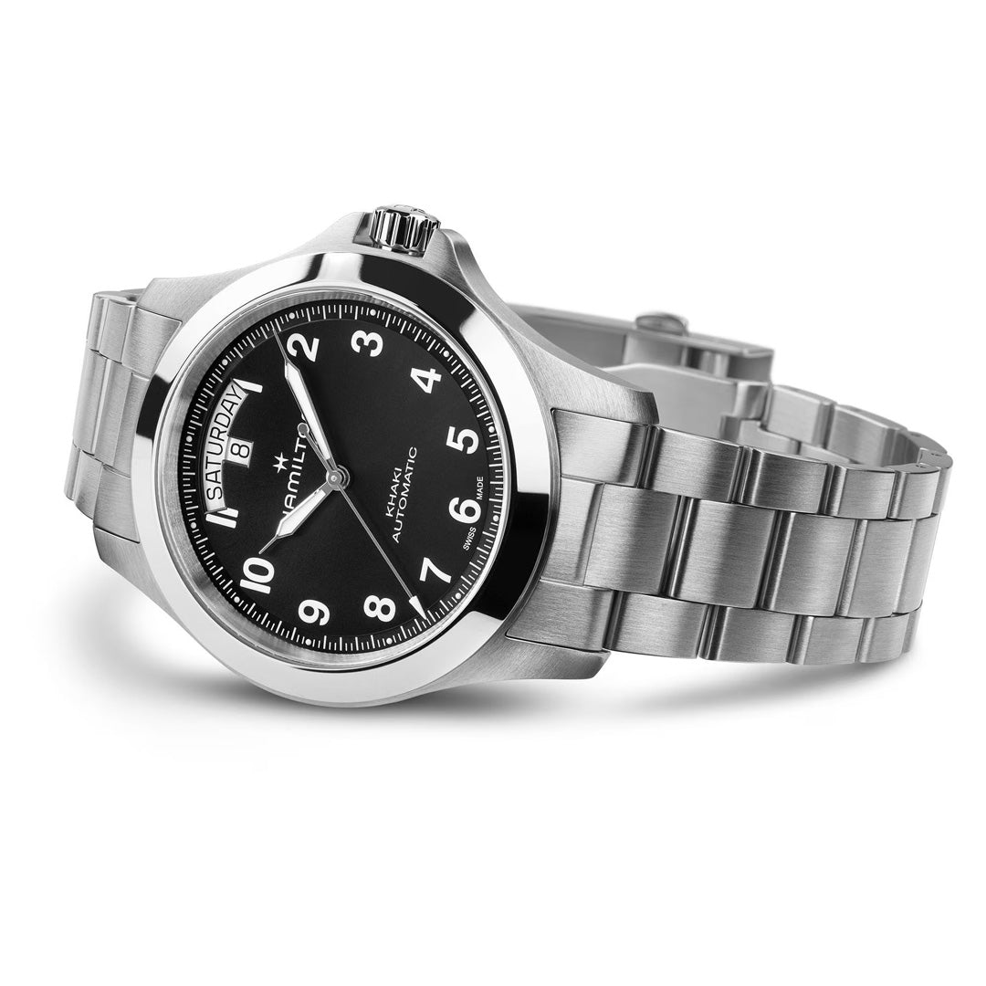 The Hamilton Khaki Field King Auto 40mm Watch by Hamilton Watch features a silver stainless steel case, black dial with white Arabic numerals, day-date display, and metal link bracelet, shown at an angle to highlight its design.