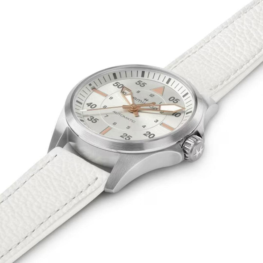 The Hamilton Khaki Aviation Pilot Auto 36mm Watch by Hamilton Watch is a silver wristwatch featuring a white leather strap and a silver dial. Its face showcases silver and orange markers enhanced with Super-LumiNova for visibility, an automatic movement marked at minute intervals, and a straightforward bezel design.