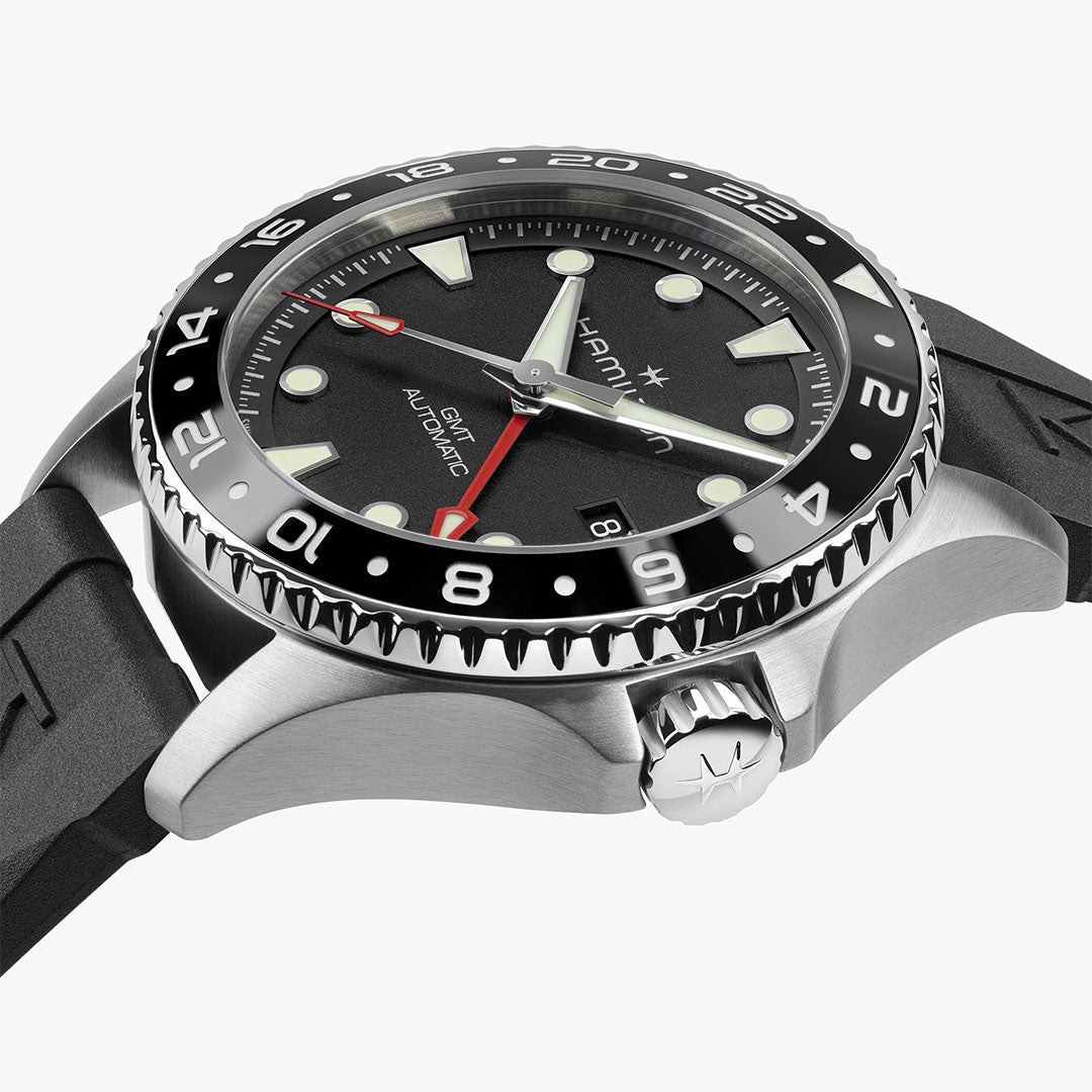 A close-up of the Hamilton Watch Khaki Navy Scuba Auto GMT 43mm featuring a black and red bezel, black dial, luminous markers, date window, and a black rubber strap against a white background.