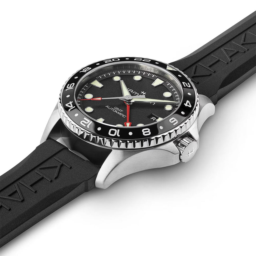 A close-up side view of the Hamilton Khaki Navy Scuba Auto GMT 43mm by Hamilton Watch reveals a black and silver automatic GMT watch with a black rubber strap, luminous markers, a 24-hour rotating bezel, and a visible right-side crown.