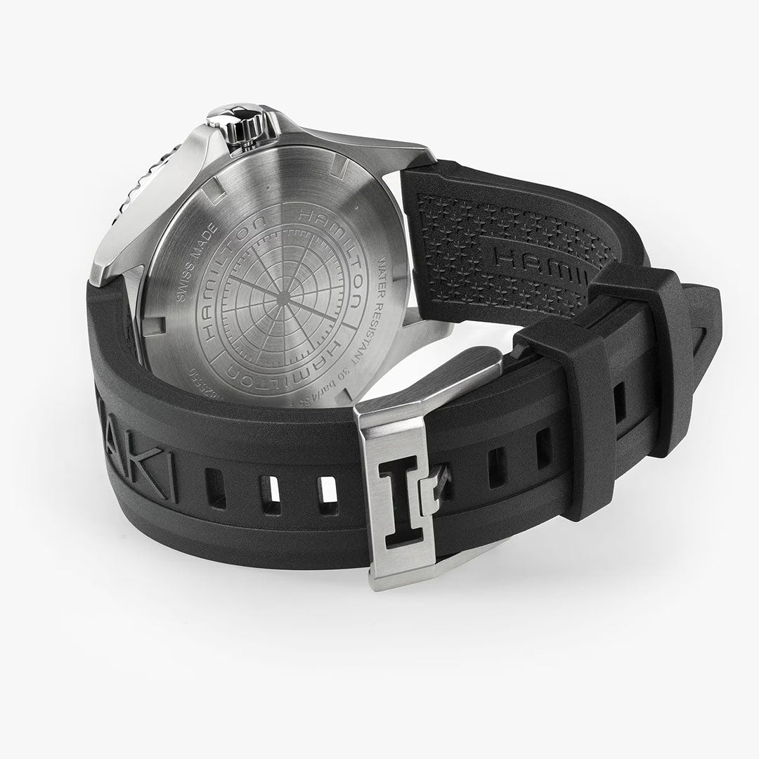 A close-up of the Hamilton Watch Khaki Navy Scuba Auto GMT 43mm highlights its black rubber strap, silver clasp, and engraved stainless steel caseback with a geometric design, reflecting the diving-inspired build of this robust timepiece.