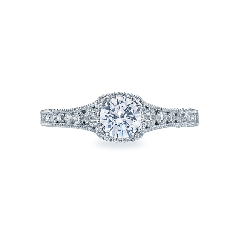 The Tacori Reverse Crescent 18K White Gold Round Brilliant Hidden Halo Diamond Engagement Ring by Tacori exudes contemporary glamour with its round central diamond encircled by smaller stones. The intricately designed band is adorned with additional tiny diamonds, creating the stunning appearance of a diamond crown on your finger.