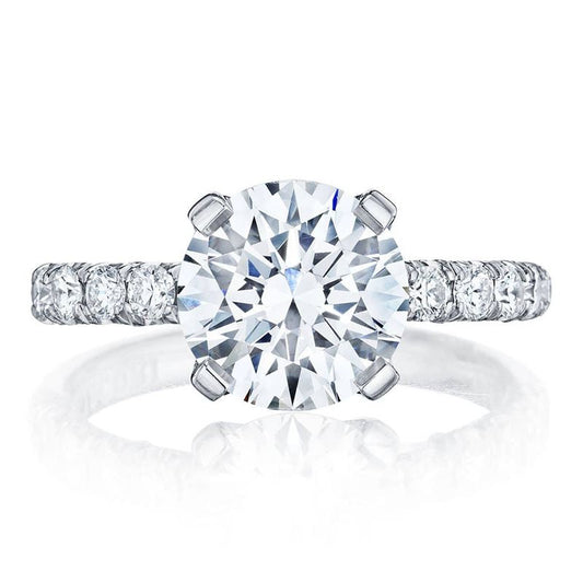 The Tacori Petite Crescent Platinum Round Brilliant Solitaire Semi Mount with Diamond Band Engagement Ring showcases exquisite craftsmanship, featuring a large round brilliant diamond at the center and smaller diamonds adorning the band, all set in a stunning platinum setting.