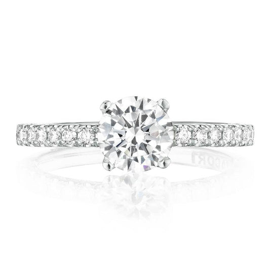 An elegant Tacori Petite Crescent engagement ring, crafted in 18K white gold, showcases a stunning round-cut center stone on a slender band. The ring is adorned with small round diamonds along the diamond-studded band, and its brilliance is captured against a white background.