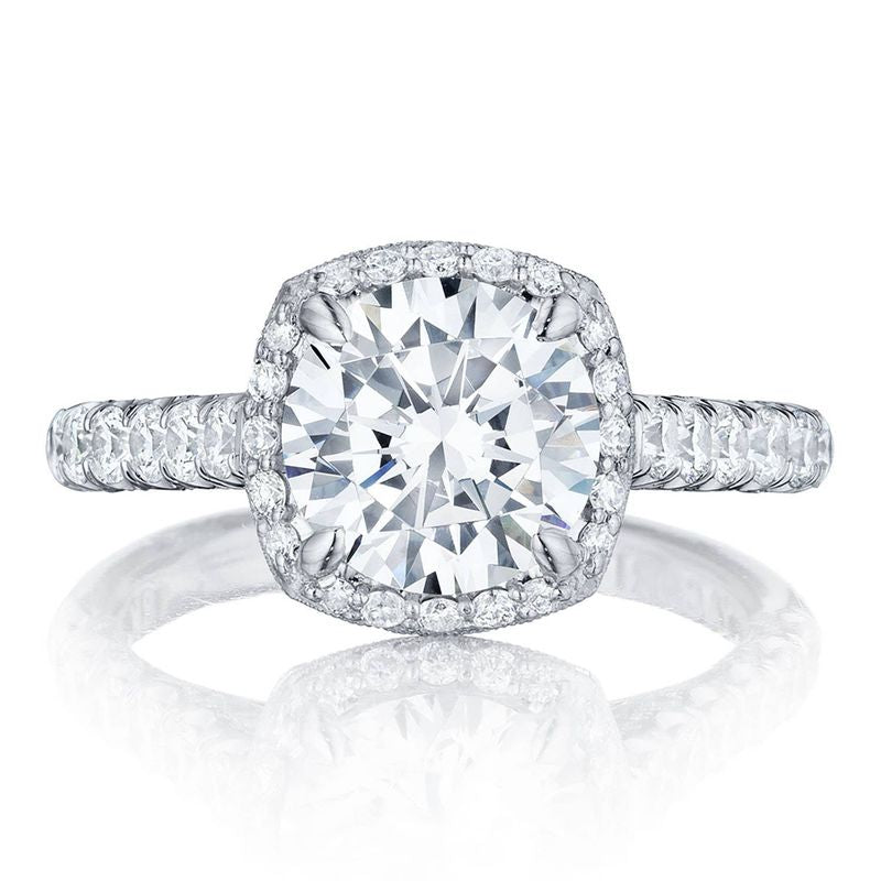 The Tacori Petite Crescent Platinum Cushion Semi Mount Engagement Ring features a stunning close-up of its large center diamond encircled by a halo of smaller diamonds. This Tacori masterpiece has a band adorned with pave diamonds, accentuating the cathedral foundation's sparkle and brilliance.
