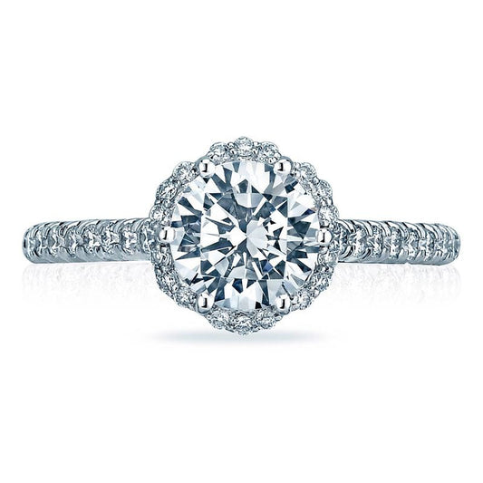 The Tacori Petite Crescent 18K White Gold Round Brilliant Semi Mount Engagement Ring showcases a dazzling design featuring a large round diamond at its center, encircled by a halo of smaller diamonds. The band is adorned with additional small diamonds, creating an intricate and sparkling look characteristic of the Petite Crescent style.