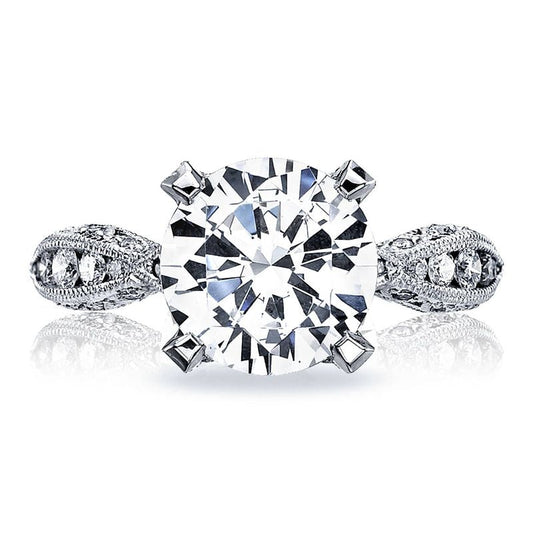 The Tacori Classic Crescent RoyalT Platinum round brilliant solitaire semi mount engagement ring showcases a large round central diamond, surrounded by smaller G color diamonds set in an ornate band design.