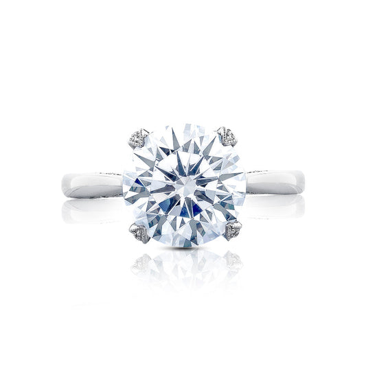 The Tacori Simply Tacori RoyalT engagement ring features a stunning round brilliant solitaire diamond elegantly set in a Cathedral foundation. This exquisite piece is crafted in platinum, boasting a simple and refined look with decorative diamond accents on the prongs. It is beautifully showcased on a pristine white background.