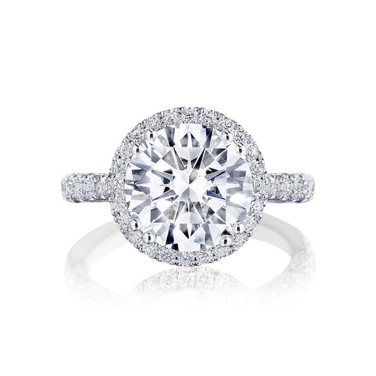 A Tacori Petite Crescent RoyalT Platinum engagement ring, showcasing a prominently round brilliant diamond surrounded by a halo of pavé-set diamonds, with the band also embellished with small diamonds.