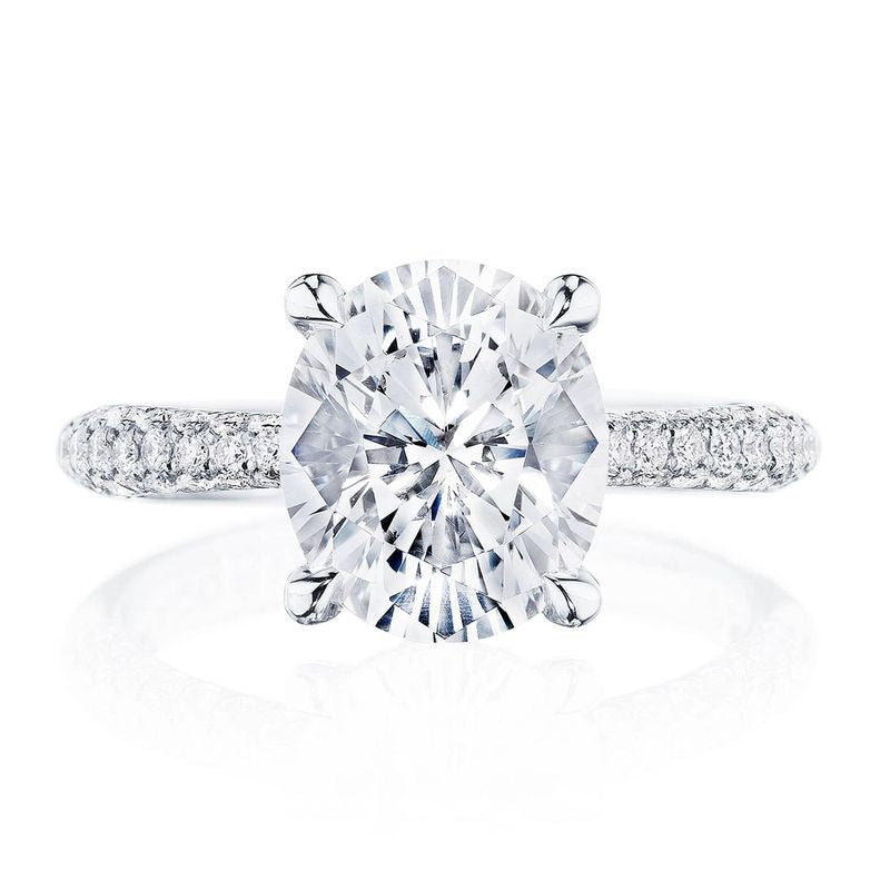 The Tacori Founder's Collection RoyalT Platinum Oval Solitaire Semi Mount with Diamond Band Engagement Ring showcases an elegant oval center diamond in a classic four-prong setting. The band, embellished with smaller diamonds, enhances the solitaire design's brilliance. The ring is exquisitely presented against a white background.