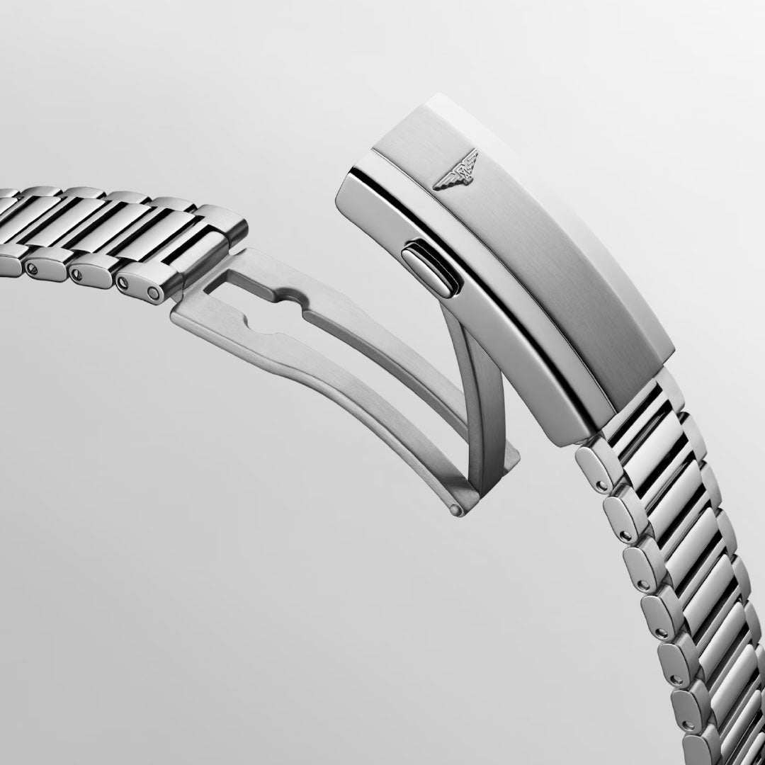 A close-up of the Longines Conquest Heritage Automatic 40mm Watch's stainless steel bracelet and partially open deployment clasp highlights its modern locking mechanism against a light gray background.