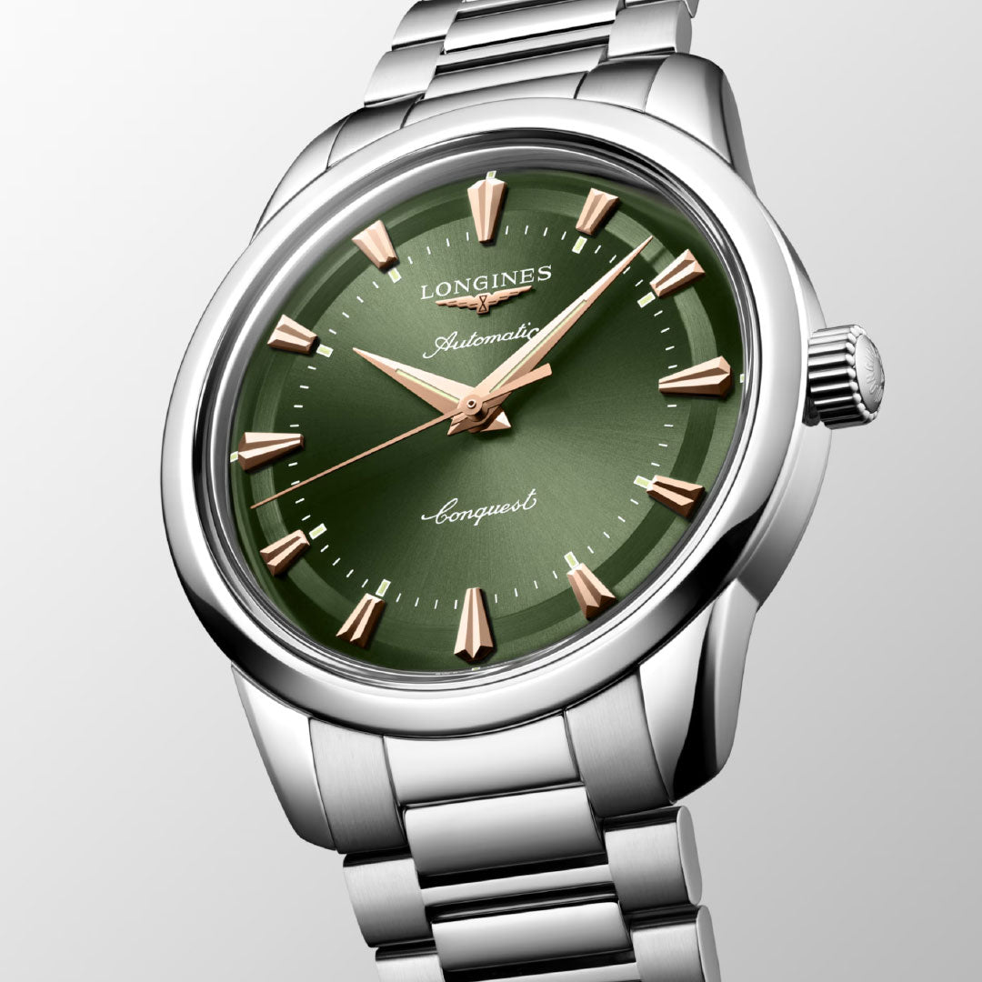 The Longines Conquest Heritage Automatic 40mm Watch features a stainless steel case, green dial, gold hour markers and hands, and displays "Automatic" and "Conquest," blending vintage design with modern technology. Time shown: 10:08:37.