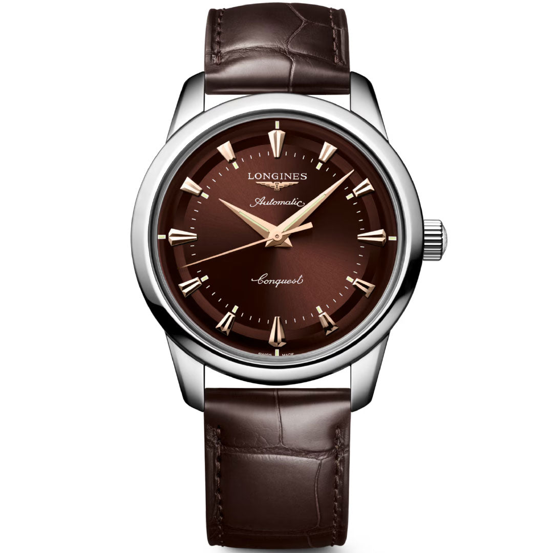 The Longines Conquest Heritage Automatic 40mm Watch features a brown dial, silver case, gold markers and hands, and a brown leather strap. "Longines," "Automatic," and "Conquest" are displayed on the dial, highlighting its vintage style.