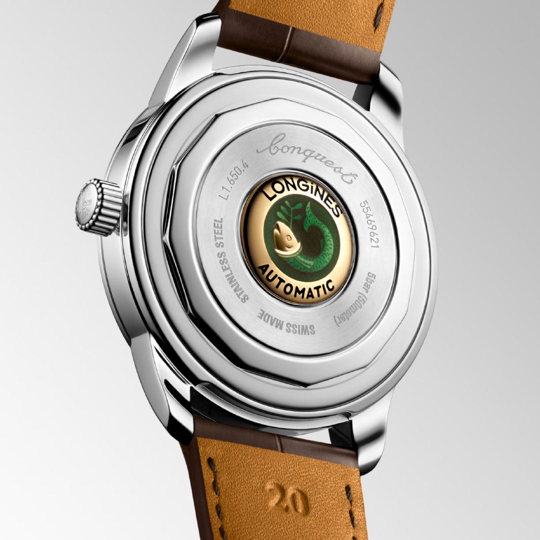 The Longines Conquest Heritage Automatic 40mm Watch features a stainless steel case, engraved logo, vintage details, visible movement with green emblem on the back, and a brown leather strap embossed with the number 20.