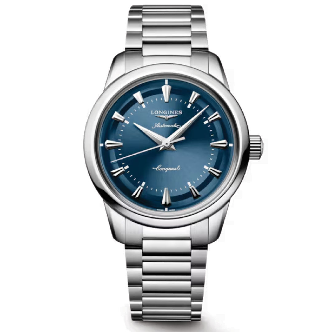 The Longines Conquest Heritage Automatic 38mm Watch features a stainless steel case, metallic blue dial with silver markers and hands, "Automatic" and "Conquest" on the face, and a stylish vintage-inspired metal link bracelet.