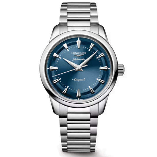 The Longines Conquest Heritage Automatic 38mm Watch features a stainless steel case, metallic blue dial with silver markers and hands, "Automatic" and "Conquest" on the face, and a stylish vintage-inspired metal link bracelet.