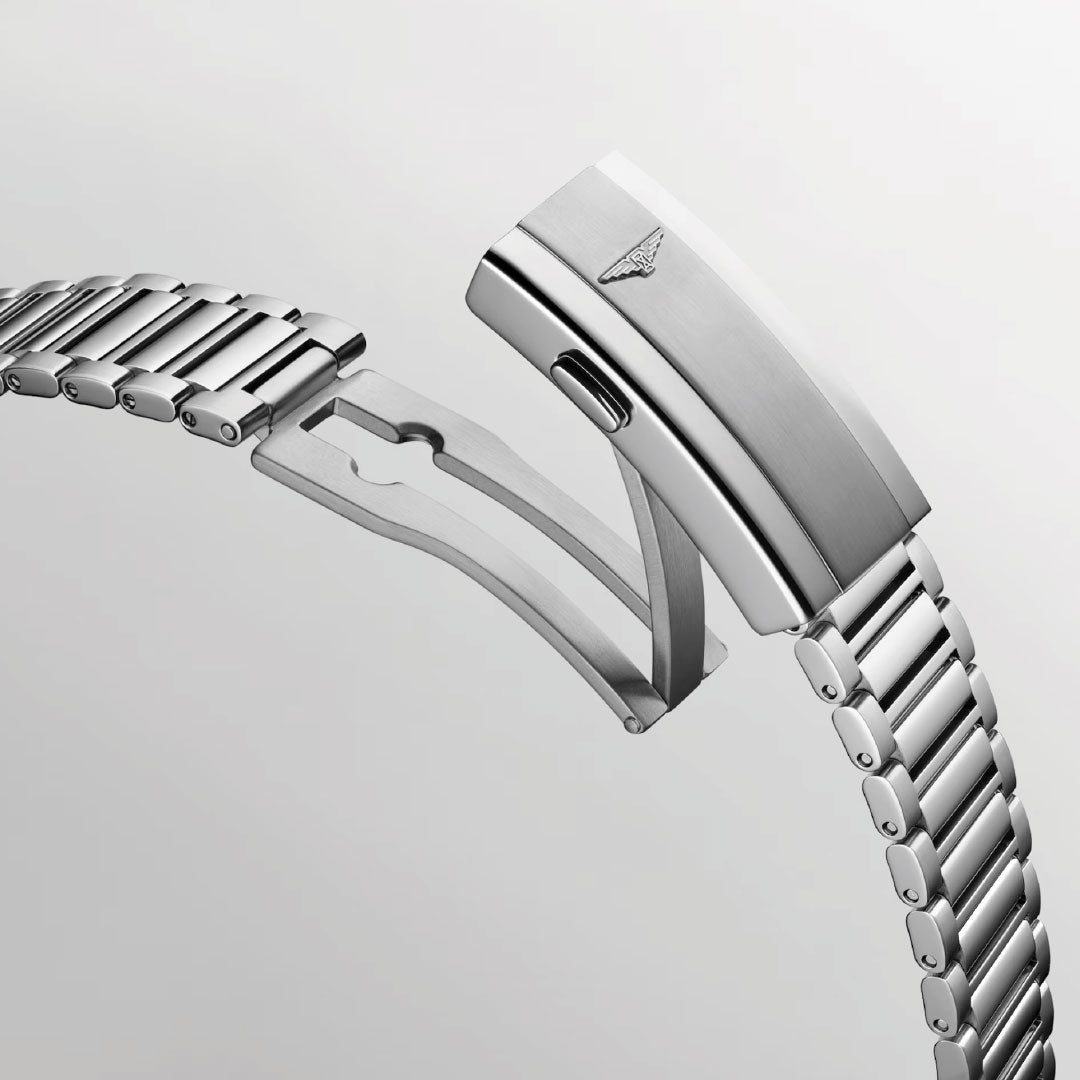 A close-up of the Longines Conquest Heritage Automatic 38mm stainless steel bracelet with a folding clasp, engraved logo, and polished brushed finish. The vintage-inspired design stands out against a light gray background.