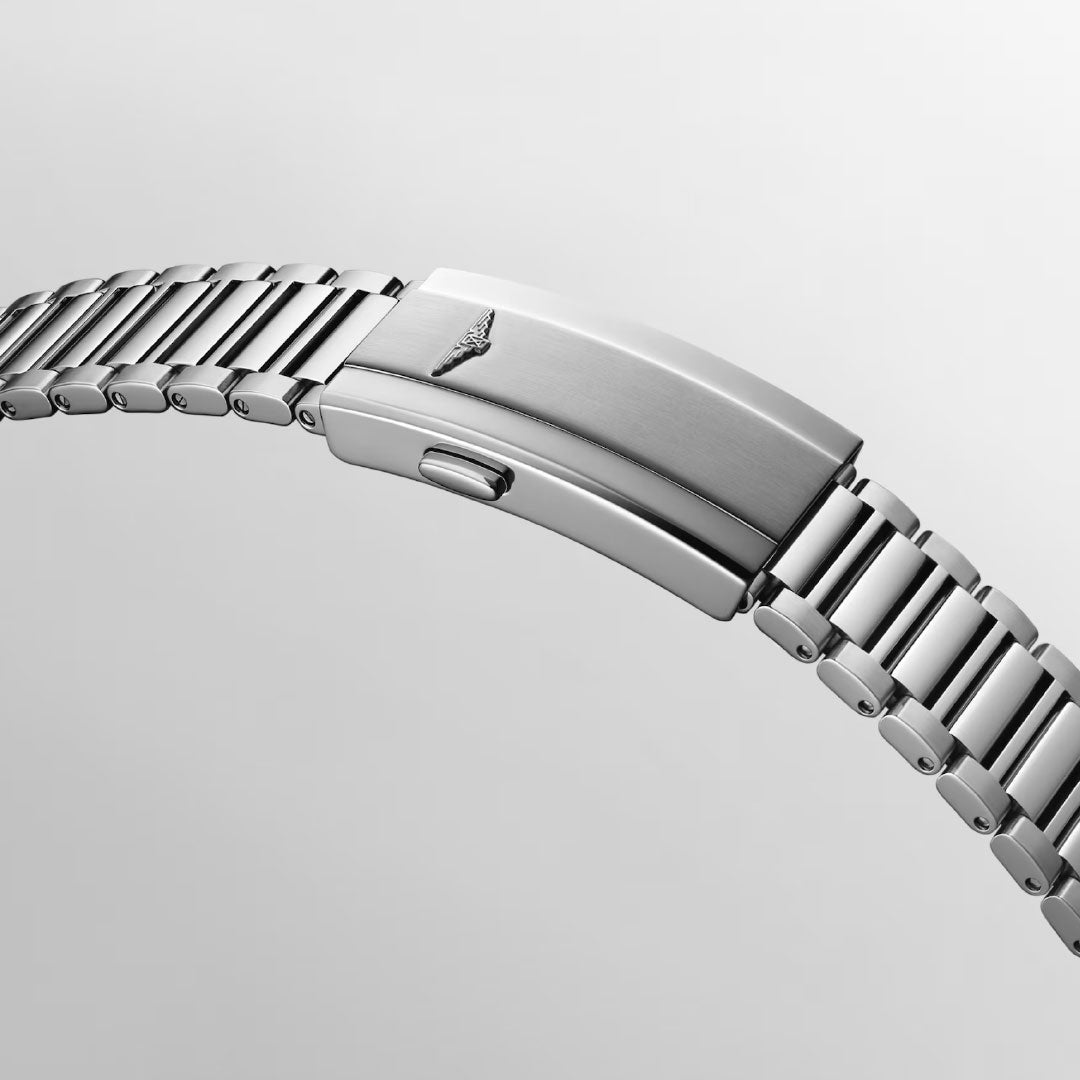 A close-up of the Longines Conquest Heritage Automatic 40mm watch bracelet shows its silver metal finish, folding clasp, and engraved winged emblem, highlighting the vintage design against a plain light gray background.