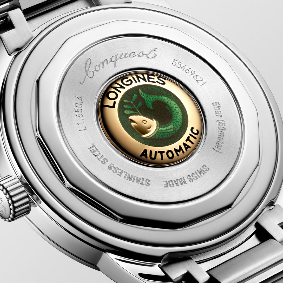 Close-up of the Longines Conquest Heritage Automatic 40mm Watch back, featuring a gold and green fish emblem with engraved "Conquest," "Swiss Made," and serial numbers—a tribute to vintage Longines design.