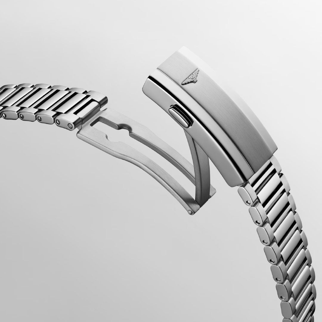 A close-up of the Longines Conquest Heritage Automatic 40mm Watch’s stainless steel bracelet with a deployment clasp showcases its engraved logo and locking mechanism, blending vintage-inspired style with modern craftsmanship against a plain light background.