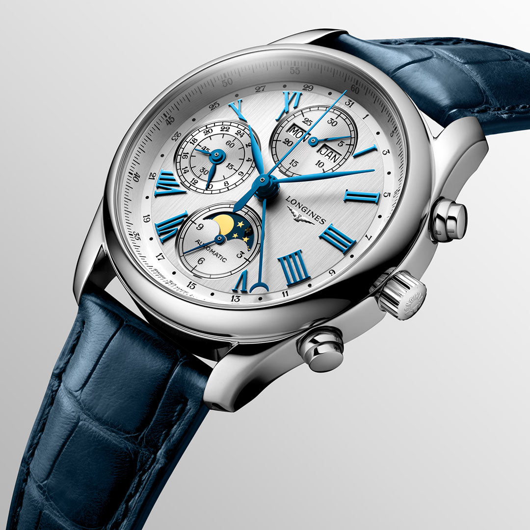 The Longines Master Collection Automatic Moonphase 40mm Watch features a silver and blue dial with Roman numerals, multiple subdials, moon phase display, a blue leather strap, and polished stainless steel case—showcasing Longines craftsmanship.