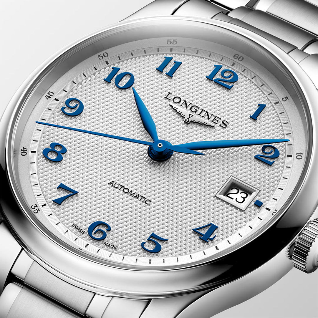 A Longines Master Collection Automatic 39mm watch featuring a silver case, textured white dial with blue numerals and hands, date display at 3 o’clock, and a metallic strap. Exemplifying Swiss watchmaking excellence by Longines, the timepiece is set to 10:09:35.
